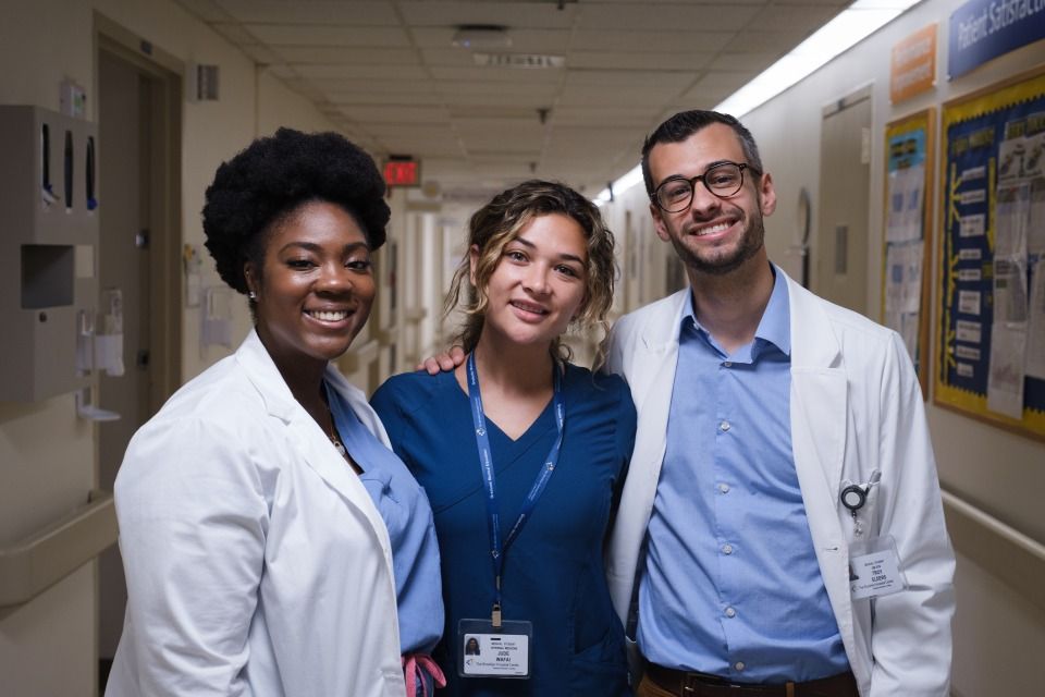 can nurses become doctors? featured image showing SGU students in white coats and scrubs pose for picture in hallway