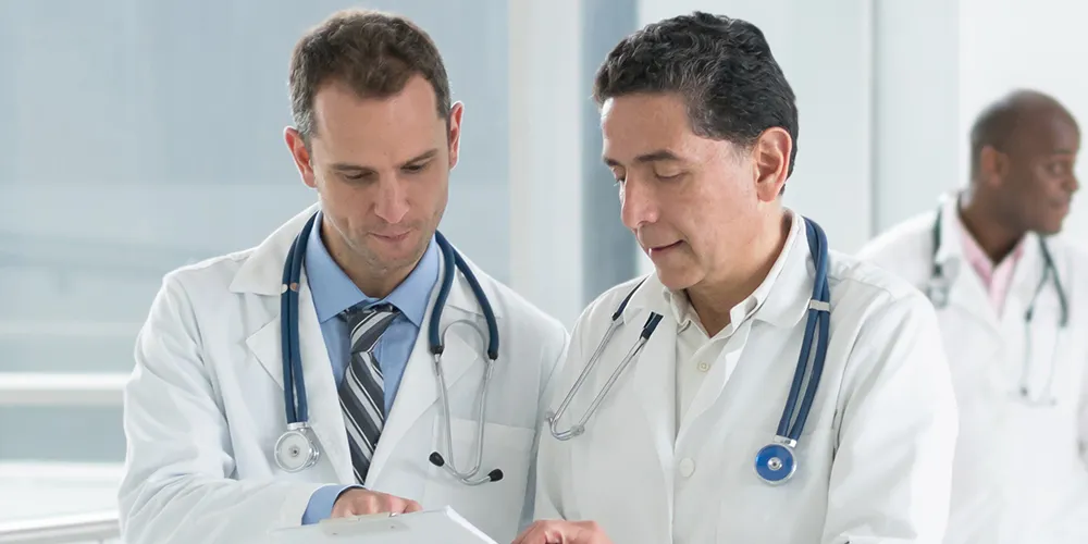 Two physicians reviewing a patient's medical chart together in a hospital