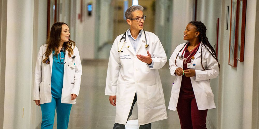 Medical residents speaking with physician in hallway