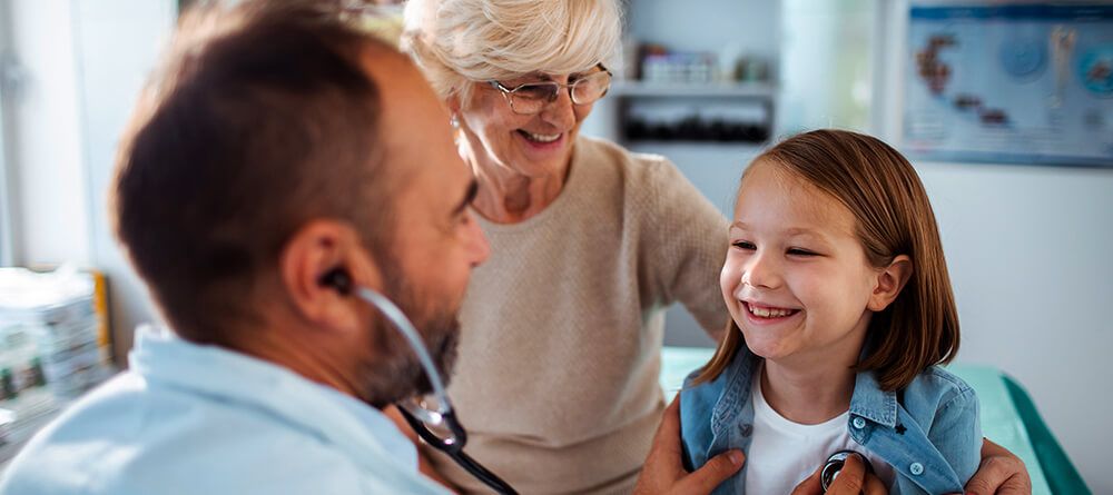A friendly doctor engages in conversation with a young girl, creating a comforting atmosphere in the clinic.
