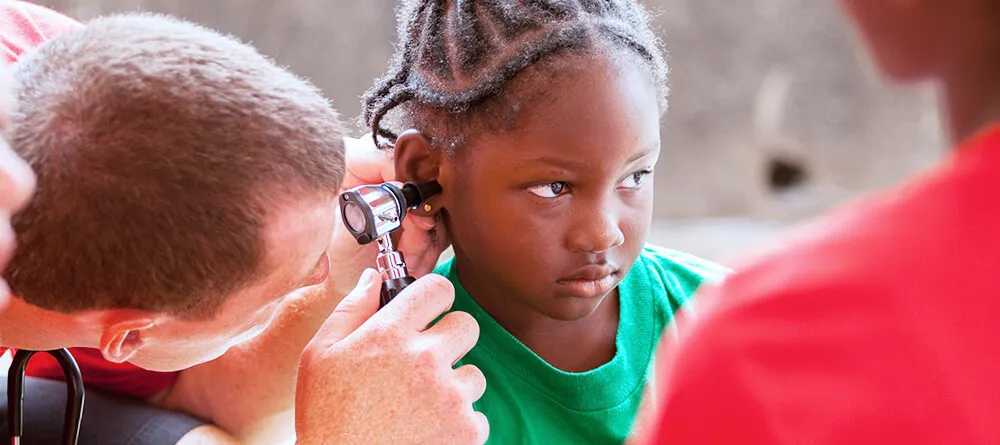Pediatrician inspecting child's ear
