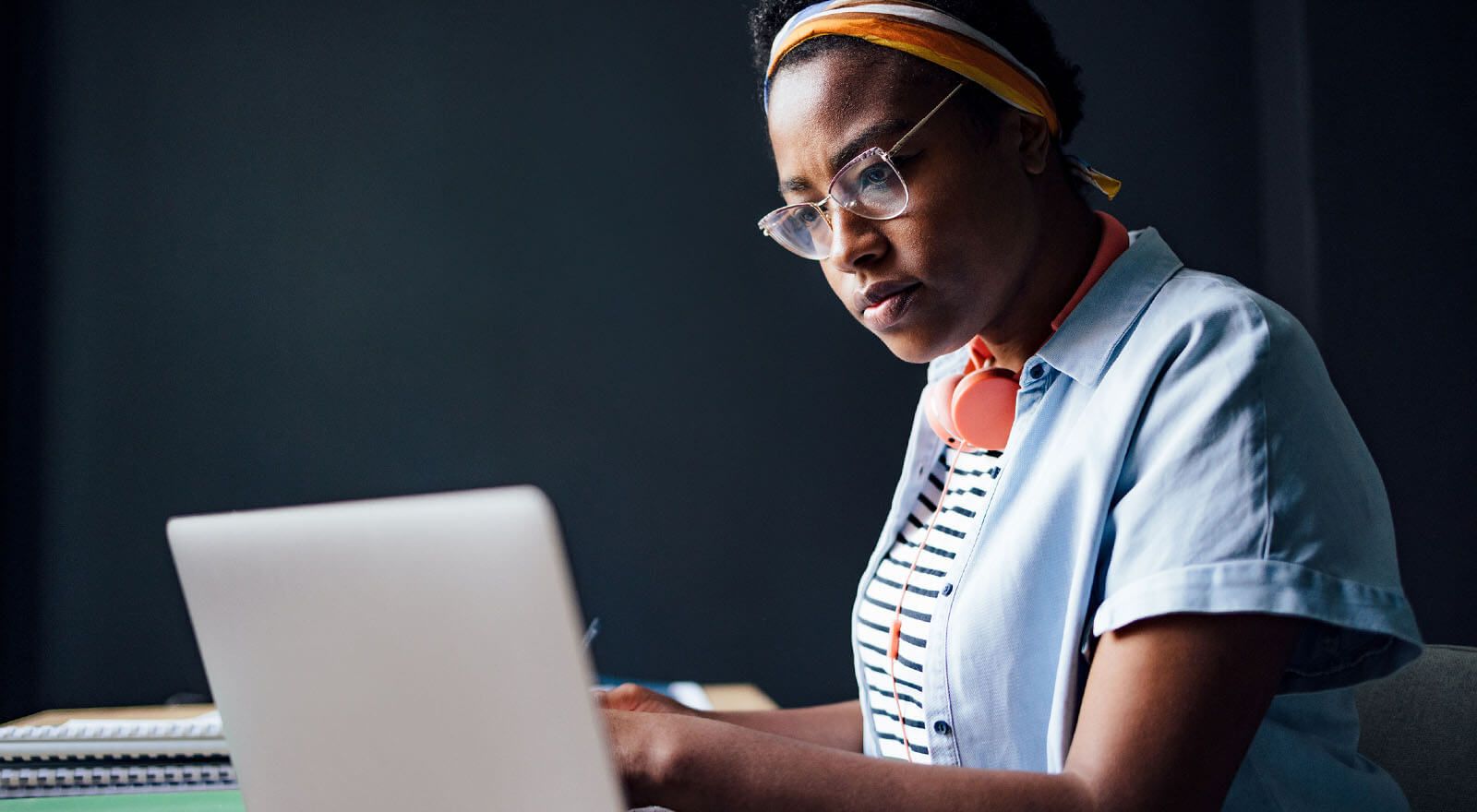 A female pre-med student with headphones, intensely focused on her laptop while preparing for the MCAT exam.