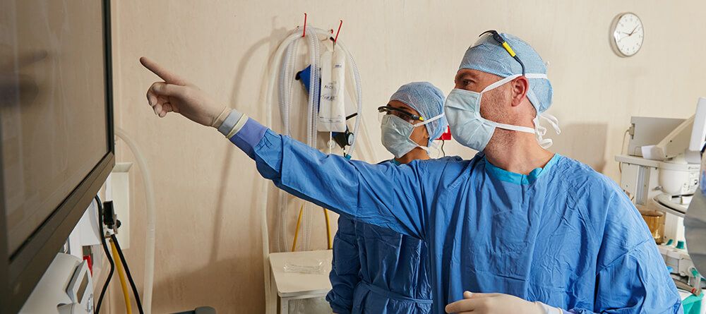 A pair of surgeons discussing a patient’s medical scans during surgery.