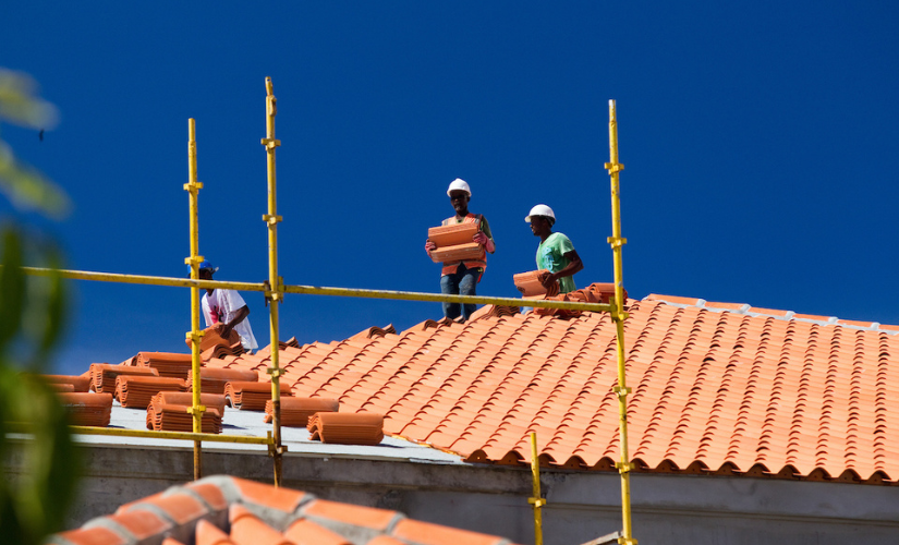 Construction workers in hard hats laying roof tiles in Grenada, illustrating a focus on workplace safety and health by an SGS student. News