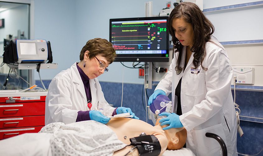 Two female medical professionals practicing CPR and airway management on a patient simulator in a high-fidelity clinical skills lab. News