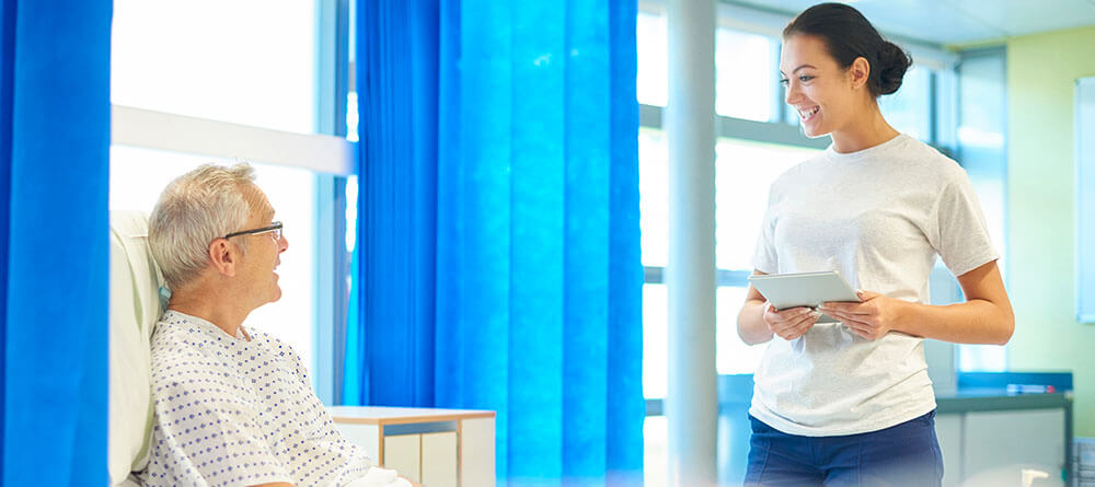 A smiling hospital volunteer speaks with a patient.