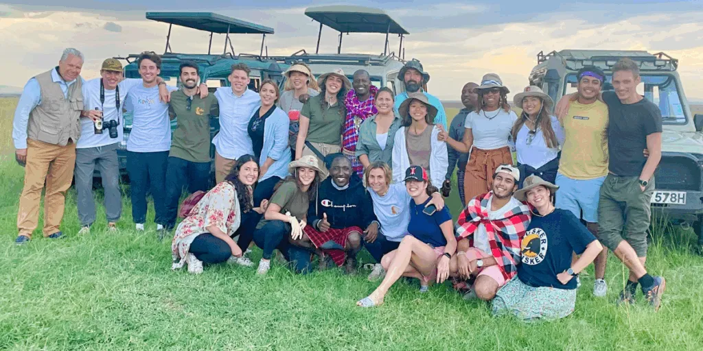 SGU students and medical professionals on a global health initiative posing with a safari guide in front of jeeps in Kenya
