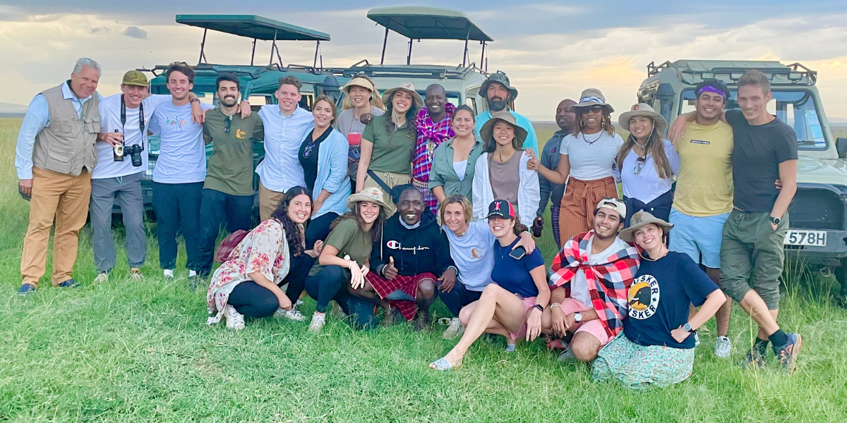 SGU students and medical professionals on a global health initiative posing with a safari guide in front of jeeps in Kenya