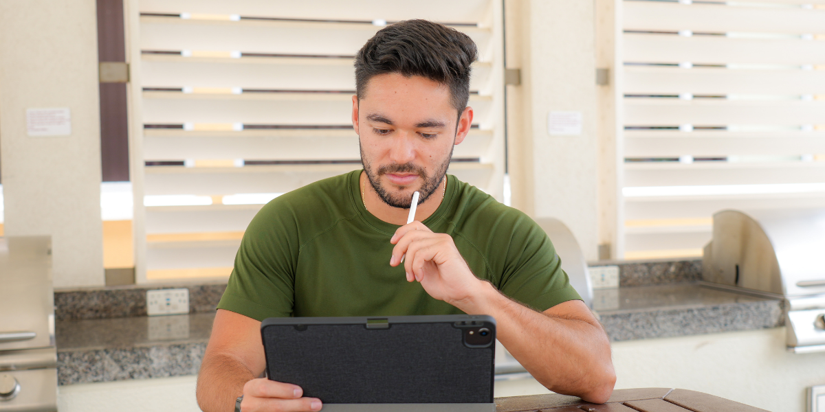 A man in a green shirt reads over his request for letters of recommendation from his professor