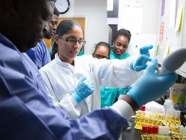 SGU students in laboratory with pipette and test tubes.