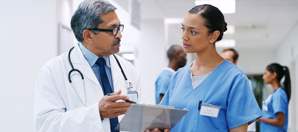 Pre-med student speaking with a physician while job shadowing.