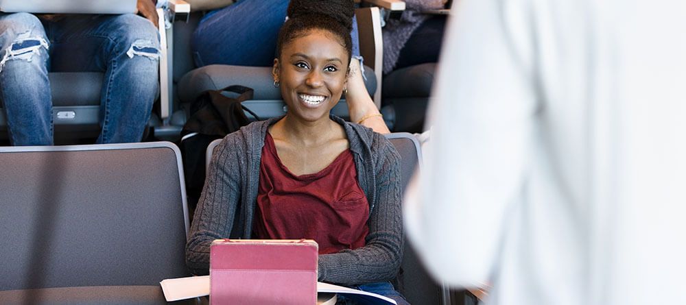 Smiling student sits in lecture hall listening to speaker