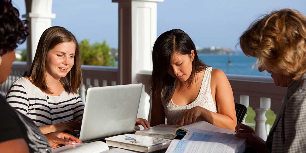 A medical school applicant reviewing GPA and MCAT score charts on a laptop, with a white coat or medical school setting subtly visible in the background.